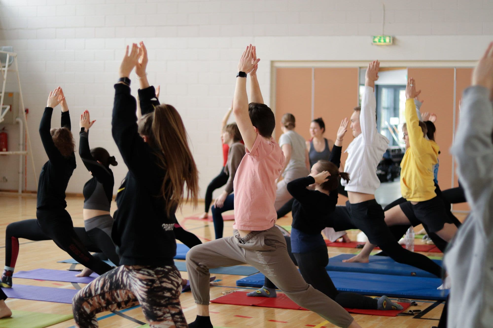 Ühistreening spordisaalis, osalejad joogaasendis mattidel